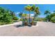 Circular brick-paved entrance featuring a small gazebo and lush tropical landscaping in a sunny community at 8403 Placida Rd # 205, Placida, FL 33946
