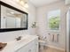 Clean bathroom featuring a single sink vanity, toilet, shower with glass door, and window for natural light at 867 Macaw Cir, Venice, FL 34285