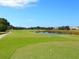 An expansive golf course with manicured greens, water feature, and clear blue sky at 867 Macaw Cir, Venice, FL 34285