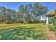 Lush backyard featuring mature trees, offering shade and privacy with green grass at 9312 Coachman Dr, Venice, FL 34293