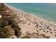 Scenic aerial view of a vibrant beach scene with sunbathers, umbrellas, and clear turquoise water at 9312 Coachman Dr, Venice, FL 34293