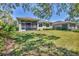 Home exterior featuring a screened-in lanai, lush green lawn, and tropical landscaping at 9312 Coachman Dr, Venice, FL 34293