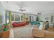 Bright living room with neutral walls, ceiling fans, large windows, and sliding glass doors to the lanai at 9312 Coachman Dr, Venice, FL 34293