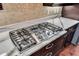 Close-up of a modern gas range on a marble countertop with dark wood cabinets at 988 145Th Street Ne Cir, Bradenton, FL 34212