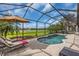 Inviting pool with brick patio inside of screened enclosure, lounge chairs, and umbrella at 988 145Th Street Ne Cir, Bradenton, FL 34212