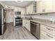 Updated kitchen with stainless appliances, granite counters, white cabinets, and grey wood-look floors at 1001 Inlet Cir # 269, Venice, FL 34285