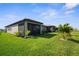 Spacious backyard featuring lush lawn, tropical plants, and screened-in patio areas at 11239 Boundless Ter, Venice, FL 34293