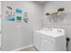 Functional laundry room with modern washer and dryer, white shelving, and decorative wall art at 11239 Boundless Ter, Venice, FL 34293