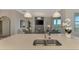 Open-concept kitchen with island seating, stainless steel sink, and connecting living area at 12140 Wellen Golf St # 401, Venice, FL 34293