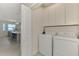 Laundry room with appliances, storage cabinets, and a view into the bright, modern kitchen at 12140 Wellen Golf St # 401, Venice, FL 34293