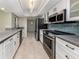 Bright kitchen featuring modern appliances, white cabinets, and a gray countertop breakfast bar at 1234 Pinebrook Way, Venice, FL 34285