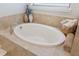 Luxurious white soaking tub is surrounded by neutral tile and decorative vases and towels at 1254 Cielo Ct, North Venice, FL 34275
