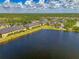 Scenic aerial view of townhomes nestled by a tranquil lake, surrounded by verdant landscapes and clear skies at 12983 Tigers Eye Dr, Venice, FL 34292