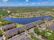 Picturesque aerial view of community with townhomes lining a lake, surrounded by lush greenery at 12983 Tigers Eye Dr, Venice, FL 34292