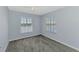 This carpeted bedroom is painted blue and has two windows overlooking the lake at 12983 Tigers Eye Dr, Venice, FL 34292