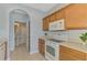 Bright kitchen features wooden cabinets, white appliances, and an arched doorway leading to the bathroom at 12983 Tigers Eye Dr, Venice, FL 34292