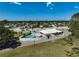 This aerial view shows a community pool, with lounge chairs and a white fence, set amongst well-maintained lawns at 131 Sandstone Cir, Venice, FL 34293
