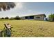 Spacious backyard with lush green grass and a bench near the home with a screened-in porch at 13452 High Springs Ave, Port Charlotte, FL 33981