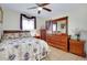 Comfortable bedroom featuring floral bedding, wood furniture, ceiling fan, and a sunlit window at 13452 High Springs Ave, Port Charlotte, FL 33981