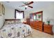 Comfortable bedroom featuring floral bedding, wood furniture, ceiling fan, and a sunlit window at 13452 High Springs Ave, Port Charlotte, FL 33981