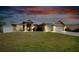 Stunning home exterior at dusk, highlighting its architectural details, manicured lawn, and inviting curb appeal at 13452 High Springs Ave, Port Charlotte, FL 33981