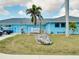 Exterior of the South Gulf Cove HOA, featuring a blue building, tropical landscaping, and ample parking at 13452 High Springs Ave, Port Charlotte, FL 33981