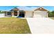 Well-manicured front lawn with long driveway leading up to two-car garage, set under a light-colored roof at 13452 High Springs Ave, Port Charlotte, FL 33981
