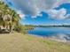 Scenic view of a calm lake with a private dock, surrounded by lush greenery and a blue sky with clouds at 13452 High Springs Ave, Port Charlotte, FL 33981
