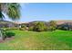 Green backyard with lush lawn, tropical plants, and screened-in lanai, perfect for enjoying outdoor living at 13897 Umbria St, Venice, FL 34293