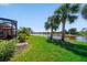 Beautiful backyard with palm trees, lush grass, and screened patio, offering serene water views at 13897 Umbria St, Venice, FL 34293