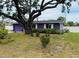 Purple exterior home with a well-manicured lawn, mature trees and a spacious driveway at 1460 Everest Rd, Venice, FL 34293