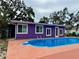 Backyard pool area with vibrant purple house, and tropical foliage at 1460 Everest Rd, Venice, FL 34293