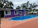 Backyard pool area with vibrant purple house, and an outdoor shower at 1460 Everest Rd, Venice, FL 34293