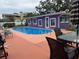 Outdoor swimming pool with a vibrant purple house backdrop and neatly landscaped surroundings at 1460 Everest Rd, Venice, FL 34293
