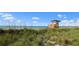 Picturesque view of the beach with a lifeguard station, tall grass, ocean, and blue sky dotted with clouds at 1555 Tarpon Center Dr # 156, Venice, FL 34285