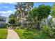 Lush landscaped exterior with palms, and walkway to condo at 1555 Tarpon Center Dr # 156, Venice, FL 34285