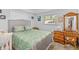 Cozy bedroom with neutral walls, a patterned bedspread, a wooden dresser, and a window with natural light at 1585 Keyway Ct, Englewood, FL 34223