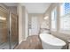 Bright bathroom featuring a soaking tub, walk-in shower, and wood-look tile floors at 19825 Bridgetown Loop, Venice, FL 34293