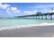 Beautiful view of the fishing pier extending into the ocean, with a sandy beach and clear blue sky at 19825 Bridgetown Loop, Venice, FL 34293