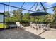 A screened in patio features an umbrella, dining table and chairs for outdoor living at 19825 Bridgetown Loop, Venice, FL 34293
