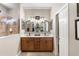 Bathroom featuring double sinks, wood cabinets, framed mirrors, sconce lighting, tiled shower and neutral wall color at 20479 Pezzana Dr, Venice, FL 34292