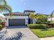 Charming home exterior showcasing a paved driveway, two-car garage, and beautiful landscaping at 208 Corelli Dr, Nokomis, FL 34275