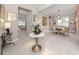 Elegant foyer featuring a marble-topped table with a floral display, light wood floors, and a view into the dining room at 208 Corelli Dr, Nokomis, FL 34275
