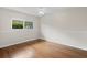 A simple bedroom with light walls, wood floors, a ceiling fan, and a large window for natural light at 214 Whispering Oaks Ct, Sarasota, FL 34232