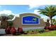 The Waterford community sign is surrounded by vibrant landscaping including red flowers, green shrubbery, and a beautiful palm tree at 25525 Lambert Ln, Punta Gorda, FL 33950