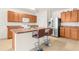 Bright kitchen featuring an island with bar stools, stainless steel appliances, and wood cabinets at 25525 Lambert Ln, Punta Gorda, FL 33950