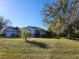 Landscaped front yard with a well-maintained lawn and mature trees surrounding the property at 2606 Trilby Ave, North Port, FL 34286