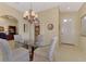 Bright dining area features an elegant chandelier and glass-top table adjacent to the front entry at 335 Auburn Woods Cir, Venice, FL 34292