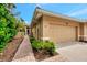 Beige home featuring a one-car garage, tile roof, and tropical landscaping with a brick walkway at 335 Auburn Woods Cir, Venice, FL 34292