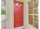 Red front door featuring sidelight window and views to tropical landscaping at 335 Auburn Woods Cir, Venice, FL 34292